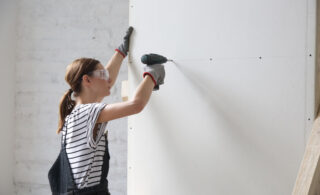 woman drilling screws into drywall