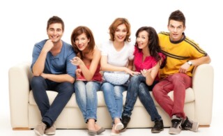 friends sitting on couch laughing at comedy movie
