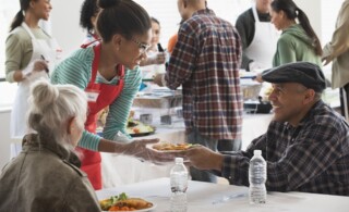 Volunteer helping the homeless by serving food at community kitchen
