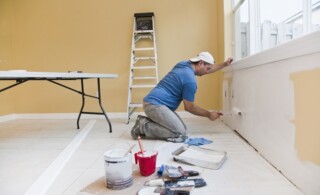 Man painting wall with roller in the house